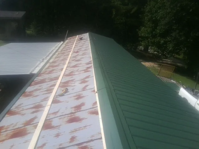 Old rusted panels beside newly installed green metal roofing — Wind Damage Roof Repair by Roofing Brothers in Lathrop