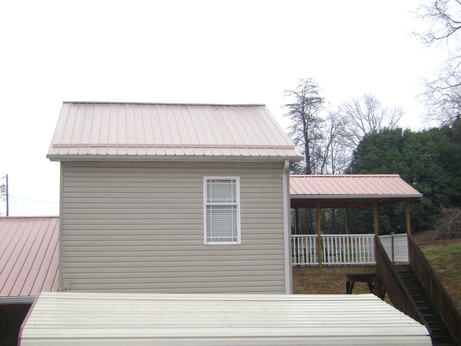 Tan metal roofs on a two story addition and attached porch, from a Roof Replacement job in Lathrop