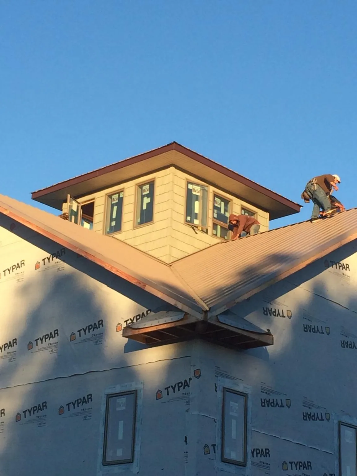 Roofers working around a rooftop cupola on a new metal roof at sunset — Roof Waterproofing in Lathrop by Roofing Brothers